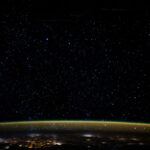 Stars glitter in the night sky above Earth's atmospheric glow