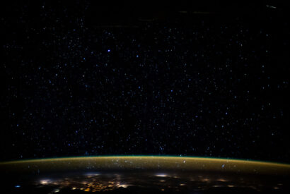 Stars glitter in the night sky above Earth's atmospheric glow